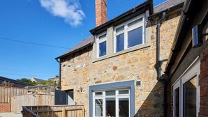 A stone house with a wooden deck, a chimney, and a garage. - Host Stay Rooftops Grey (Alnwick)