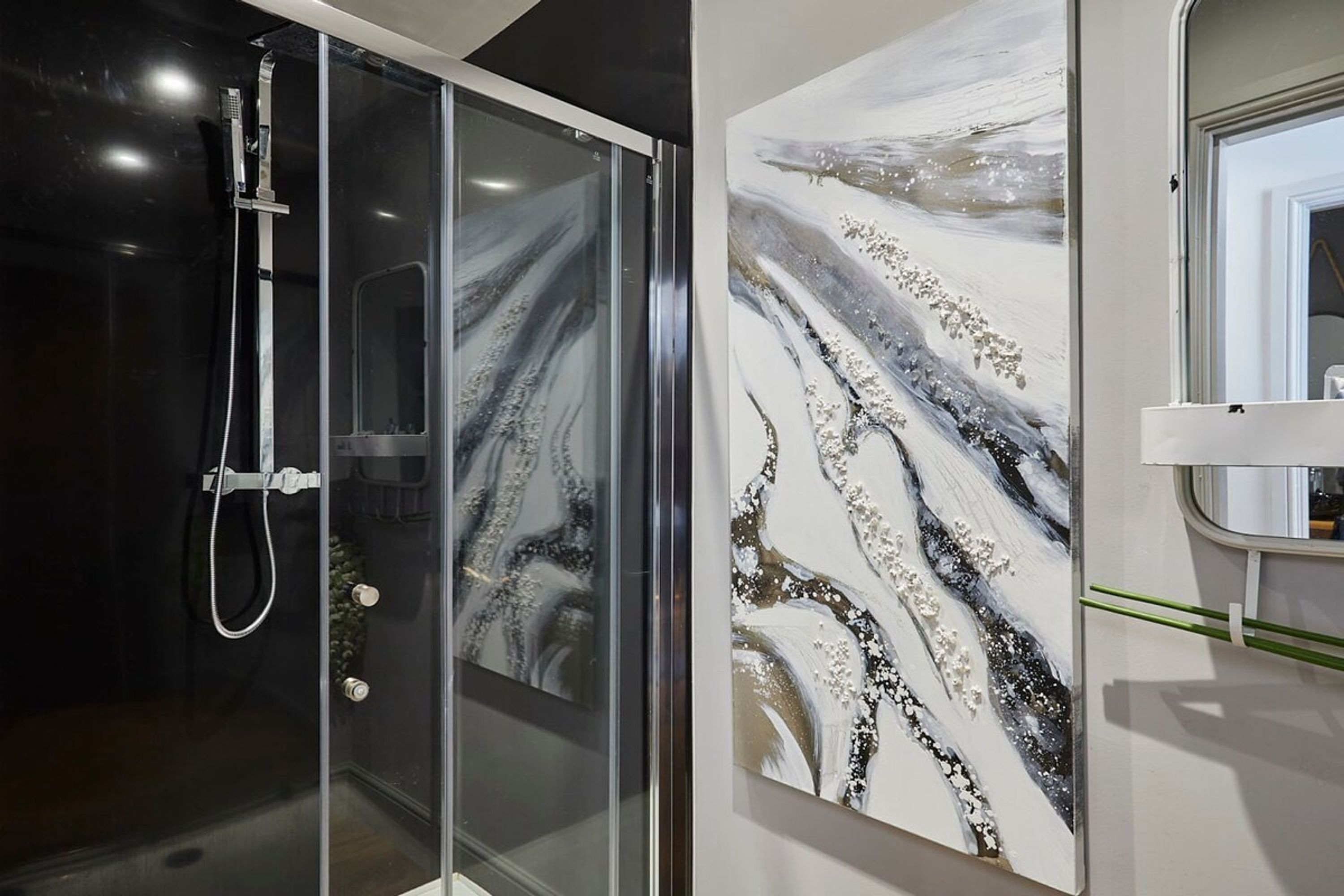 Un baño moderno con cabina de ducha de vidrio, pared de mármol y ventana con vistas.