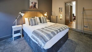 A modern bedroom with a large bed, two bedside tables, a headboard, and a painting of a bull. - Host Stay Rooftops Grey (Alnwick)