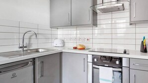 Une cuisine moderne dotée d’appareils électroménagers en acier inoxydable, de meubles blancs et d’un revêtement mural en carreaux.