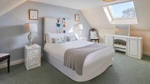 A bedroom with a bed, bedside tables, a desk, and a skylight. - Host Stay Grange Cottage (Belford)