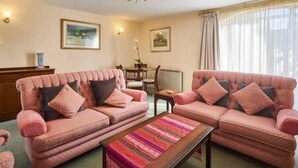 A living room with two pink sofas, a wooden coffee table, and a chandelier. - Host Stay Grange Cottage (Belford)