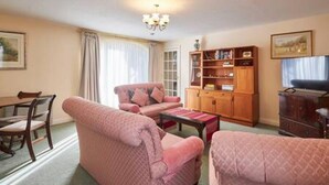 A living room with a sofa set, a wooden cabinet, and a television. - Host Stay Grange Cottage (Belford)