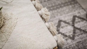 A textured white fabric with tassels, likely a throw blanket, on a wooden surface. - Host Apartments Knight St Place (Liverpool)
