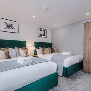 A hotel room with two beds, green headboards, white bedding, and artwork on the walls. - Host Apartments The Roscoe Coach House (Liverpool)