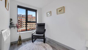 A modern room with a large window, a gray chair, a round rug, and two framed pictures on the wall. - Host Apartments The Roscoe Nest (Liverpool)