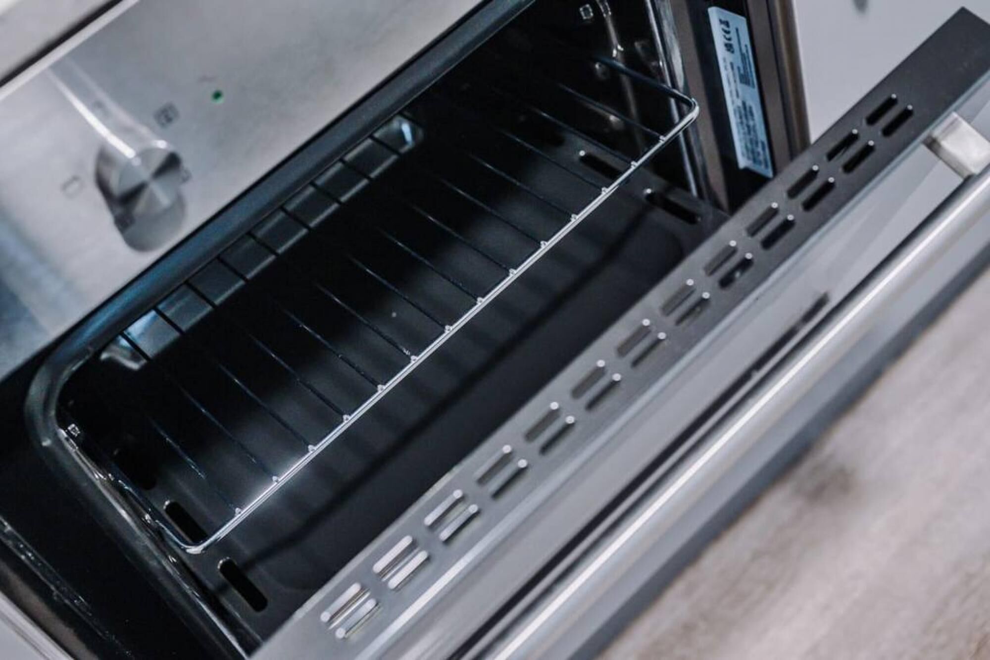 An open oven with a control panel and a label on the door.