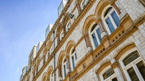 A multi-story building with classical architecture, featuring arched windows and ornate detailing. - Host Apartments Queen Square Apartment (Liverpool)