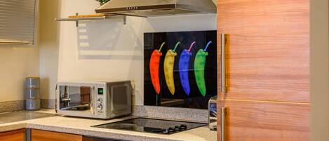 A kitchen with a toaster, microwave, stove, and a wall-mounted plant.