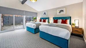 A modern bedroom with two beds, a large sliding glass door leading to a balcony, and a ceiling light fixture. - Host Apartments The Coachouse at Pilgrim St (Liverpool)