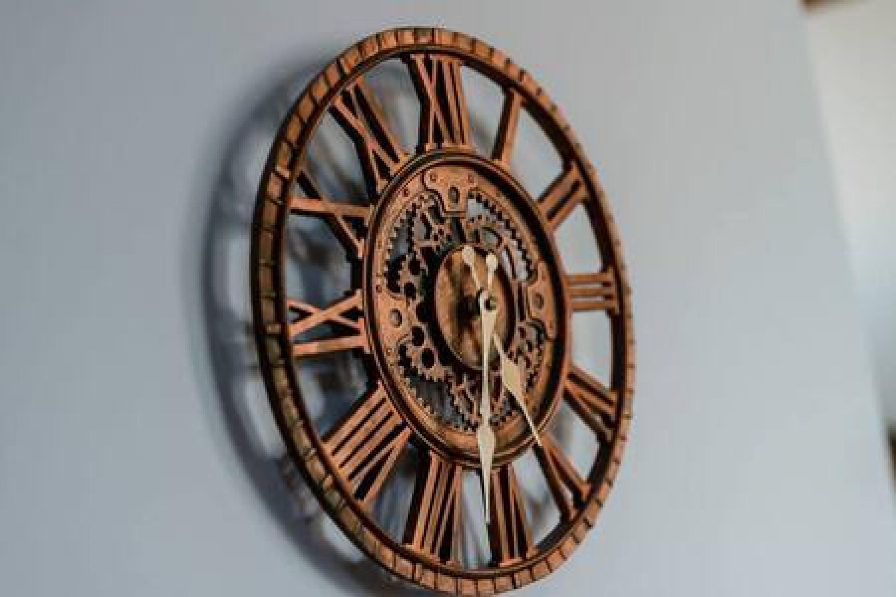 A wall-mounted clock with Roman numerals and intricate gears.