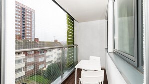 A balcony with a glass railing, a white table, and two white chairs. - Host Apartments Standish Street Living (Liverpool)