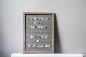 A framed sign with text inviting guests to book directly at HOSTANDSTAY.CO.UK. - Host Apartments Standish Street Living (Liverpool)