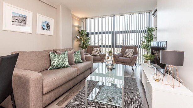 Uma sala de estar moderna com um sofá, poltronas, uma mesa de centro e uma televisão.