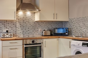 A compact kitchen with a microwave, toaster, and washing machine. - Host Apartments Ropewalks Abode (Liverpool)