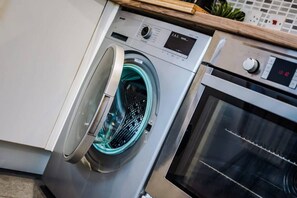 A modern kitchen with a built-in washing machine and oven. - Host Apartments Ropewalks Apt (Liverpool)