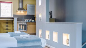 Une chambre d’hôtel moderne équipée d’un lit, d’une kitchenette et d’une salle de bain.