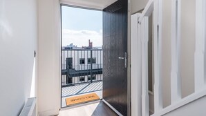 A modern apartment entrance with a view of the cityscape through a glass door. - Host Apartments The Baltic Penthouse 3 (Liverpool)