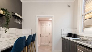 A modern kitchen with a marble countertop, dark cabinets, and a white door leading to another room. - Host Apartments Seel St Townhouse Apt I (Liverpool)