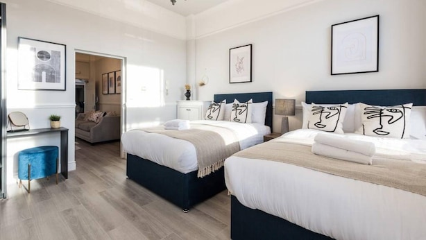 A modern hotel room with two beds, a desk, and a chair. - Host Apartments Seel St Townhouse Apt I (Liverpool)