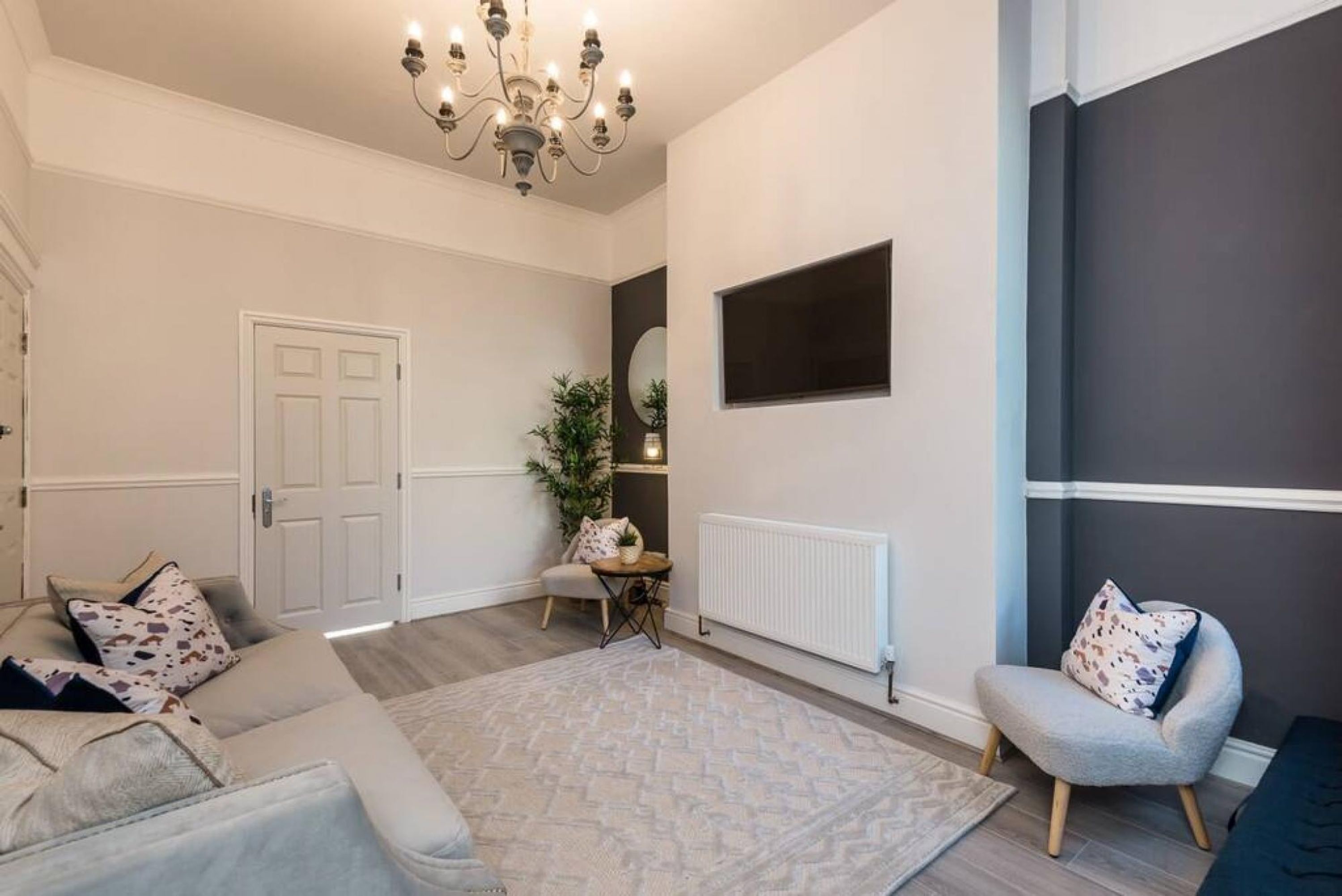 A living room with a sofa, armchair, and a patterned rug.