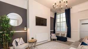 A modern living room with a grey sofa, a round mirror, a potted plant, and a chandelier. - Host Apartments Seel St Townhouse Apt I (Liverpool)