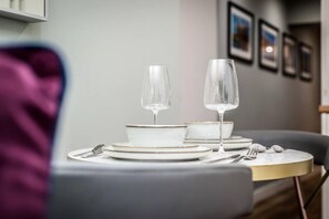 A dining table set with white plates, bowls, and two wine glasses. - Host Stay The Georgian Quarters at Bedford (Liverpool)