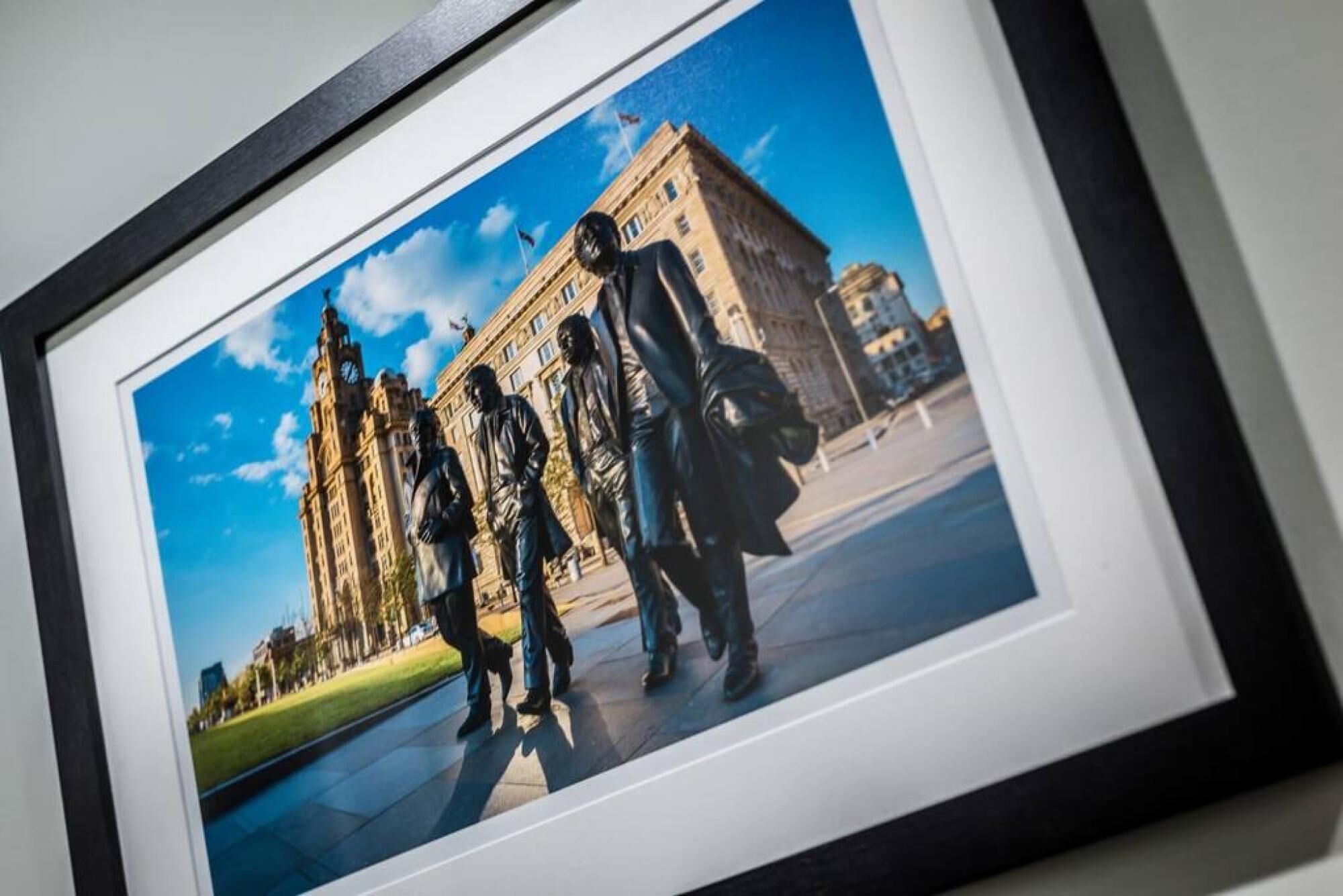A framed photograph of a building with a clock tower, a statue, and a person walking.