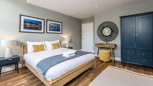 A modern bedroom with a large bed, two bedside lamps, a wooden nightstand, a round mirror, and a dark blue wardrobe. - Host Stay Catharine Quarters I (Liverpool)