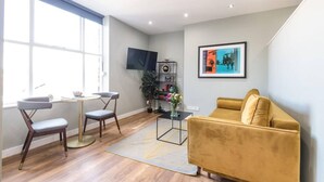 Een moderne woonkamer met een bank, twee fauteuils, een bijzettafeltje, een televisie en een boekenkast.