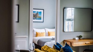 A hotel room with a bed, a desk, a chair, a small table with a glass, and a framed picture on the wall. - Host Apartments The Georgian Quarters at Bedford (Liverpool)