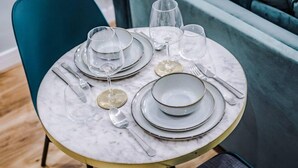 A table set with plates, glasses, and cutlery, with a teal chair and a marble table. - Host Apartments The Georgian Quarters at Bedford (Liverpool)