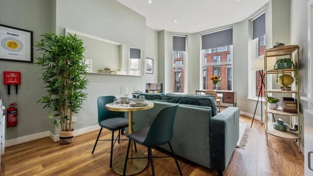 A modern living room with a green sofa, a round table, and a large plant. - Host Apartments The Georgian Quarters at Bedford (Liverpool)