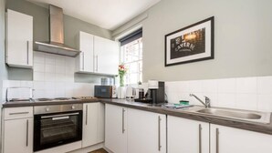 A modern kitchen with white cabinets, a built-in oven, a microwave, a coffee maker, and a sink. - Host Stay Catharine Quarters II (Liverpool)