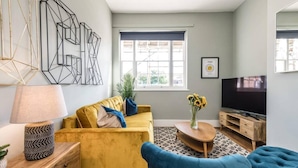 A living room with a sofa, a blue armchair, a TV, and a window with blinds. - Host Stay Catharine Quarters II (Liverpool)