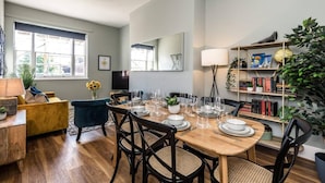 A dining area with a wooden table set for six, surrounded by black chairs with woven seats. - Host Stay Catharine Quarters II (Liverpool)