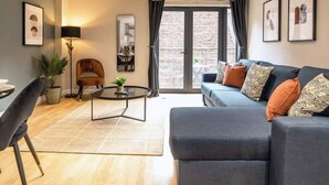 A modern living room with a grey sofa, a round coffee table, and a dining area with a chair and table.