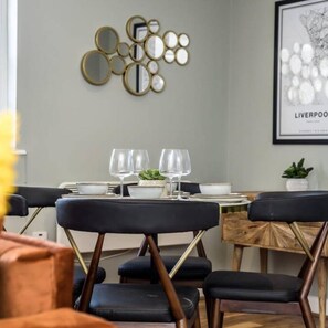 A dining area with a table set for two, two chairs, and a wall-mounted mirror. - Host Apartments Catharine Quarters III (Liverpool)