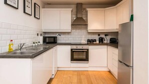 A modern kitchen with white cabinets, a stainless steel refrigerator, a microwave, and an oven.