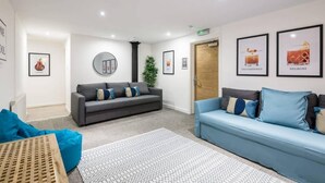 Un espace d’accueil moderne, avec deux canapés, un tapis à motifs et des tableaux encadrés accrochés aux murs.