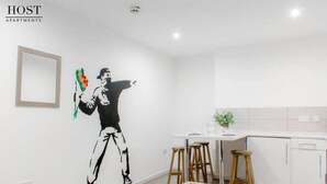 A modern kitchen with white cabinets, a wooden bench, and a bar stool. - Host Apartments Fleet Nightlife III (Liverpool)