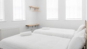 A room with two beds, white bedding, wooden headboards, and a radiator. - Host Apartments Fleet Nightlife III (Liverpool)