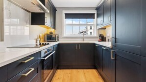 A modern kitchen with dark cabinetry, a white countertop, and a window above the sink. - Host Apartments Upper Duke Street Apartment (Liverpool)