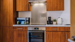 A modern kitchen with wooden cabinets, a stainless steel range hood, a built-in oven, and a microwave.
