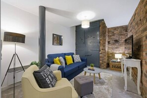 A modern living room with a blue sofa, a beige armchair, and a small round table. - Host Apartments Henry s Hideaway (Liverpool)