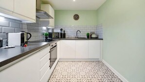 A compact kitchen with white cabinets, a black countertop, and a patterned floor. - Host Apartments Halifax House II (Liverpool)