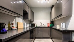 A modern kitchen with stainless steel appliances, a black countertop, and a central island. - Host Apartments The Georgian Quarters at Canning (Liverpool)