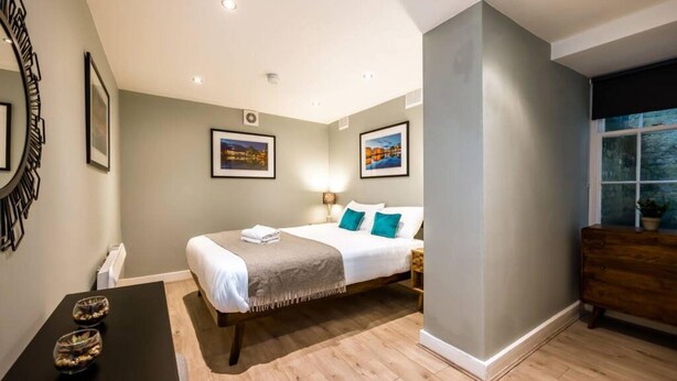 A bedroom with a bed, bedside tables, a dresser, and framed pictures on the walls. - Host Apartments The Georgian Quarters at Canning (Liverpool)