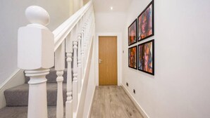 A hallway with a staircase, a wooden door, and framed artwork on the wall. - Host Apartments The Georgian Quarters at Canning (Liverpool)