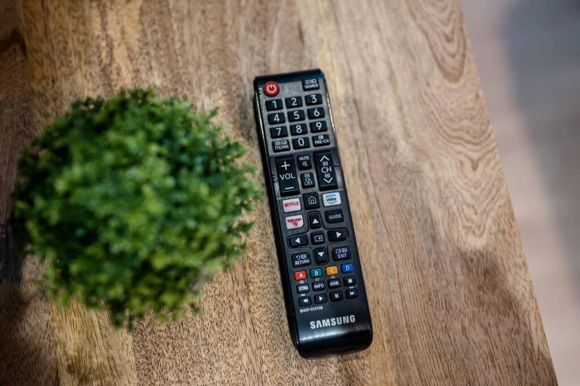 Eine schwarze Samsung-Fernbedienung auf einer Holztischplatte.